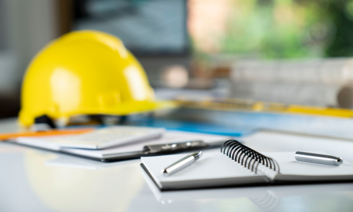 A notebook and pen surrounded by contractor supplies on a table.